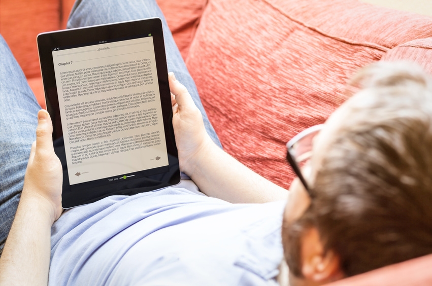 technology lifestyle concept: hipster man reading ebook on the sofa