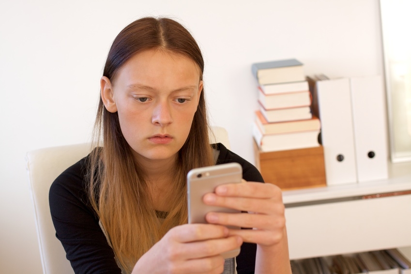 Jugendliche liest auf ihrem Handy